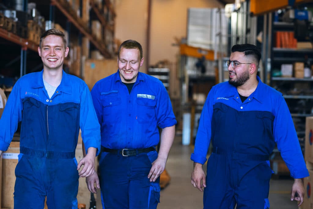 Tre kolleger i blåt arbejdstøj på værkstedet